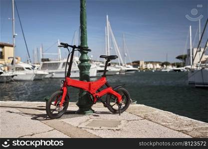         Foldable e-bike agianst pole in harbour                       