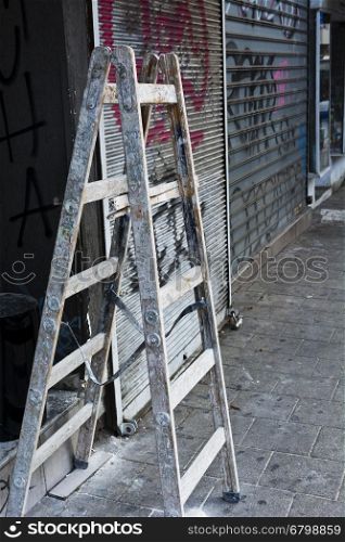 Foldable Wooden Ladder for Repairs of Shop in Tel Aviv. Splattered Ladder in the Street.