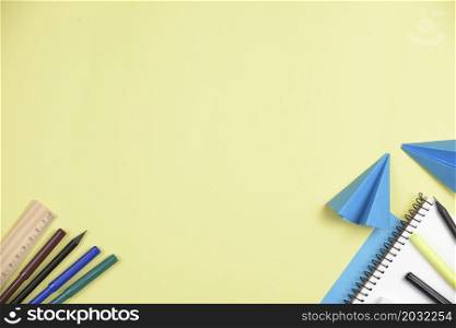 folded blue papers with office stationeries against yellow backdrop with space writing text