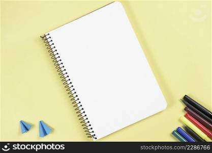 folded craft paper felt tip pen near blank spiral notepad yellow back