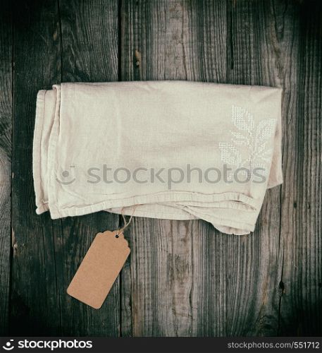 folded dishcloth tied with an empty brown tag on a gray wooden background, top view