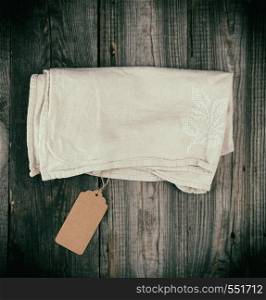 folded dishcloth tied with an empty brown tag on a gray wooden background, top view