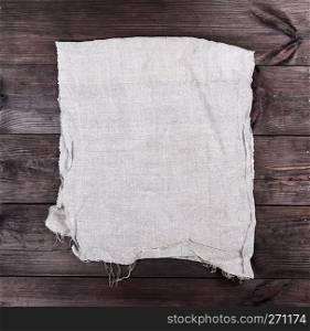 folded gray towel on brown wooden background, top view