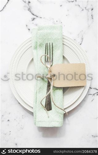 folded napkin fork tied with string blank tag white ceramic plate