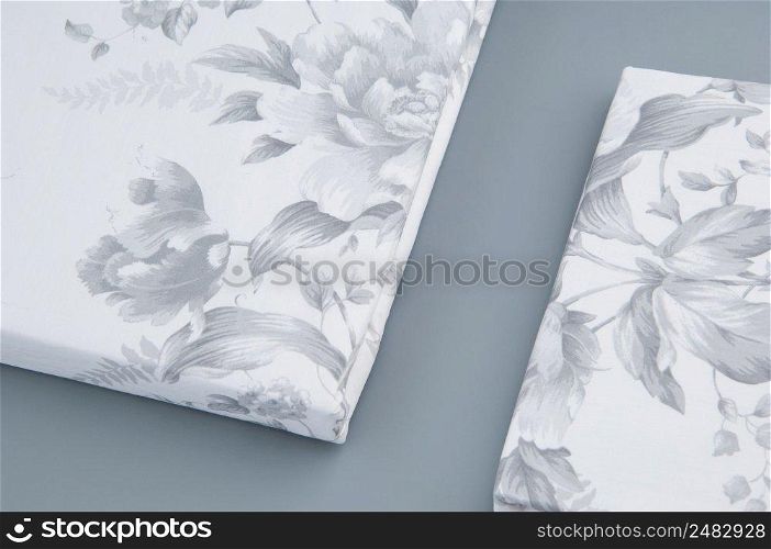 folded new bed linen with patterns on grey background, top view. bed linen on grey background