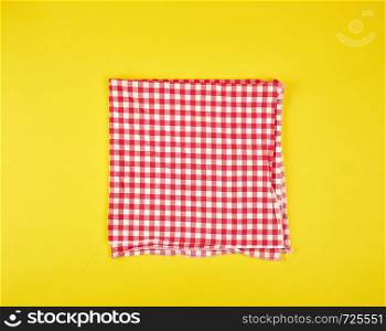 folded red kitchen towel in a cage on a yellow background, flat lay