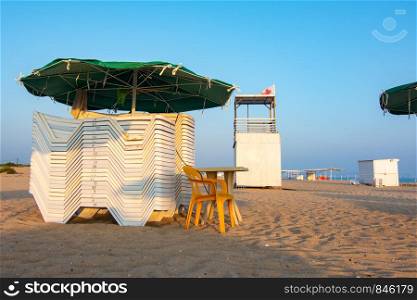 Folded sun loungers and an empty lifeguard post on a deserted sandy beach