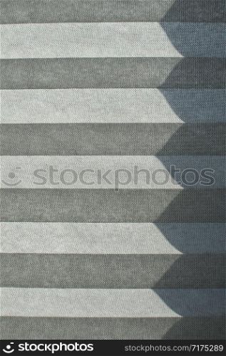 Folded textile window blind lit by sunlight closeup as background