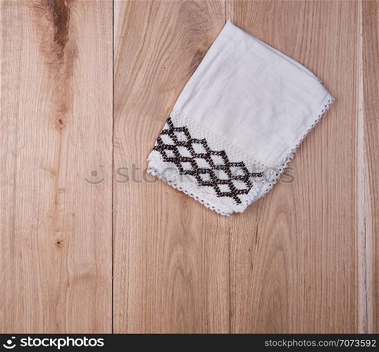 folded white towel on brown wooden background, top view