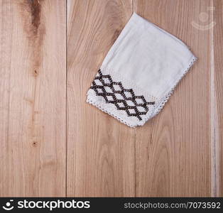 folded white towel on brown wooden background, top view