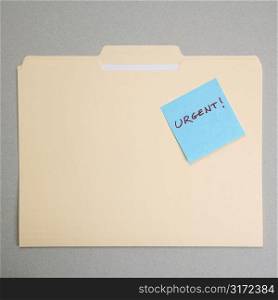 Folder with a sticky note attached reading urgent.