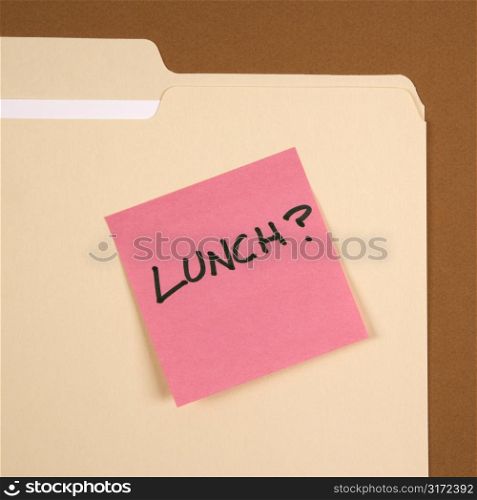 Folder with pink sticky note reading lunch on a green background.