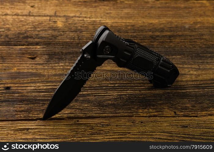 Folding pocket knife with one edge on wooden background