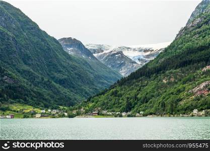 Folgefonna glacier cap in the mountains with lake and village in the foreground, Odda, Hardanger region, Hordaland county, Norway