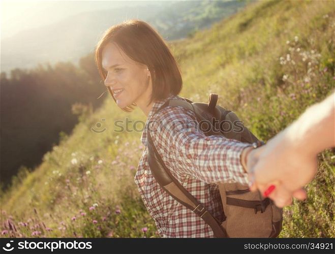 Follow me. Beautiful young laughing woman holds the hand of a man on sunny field