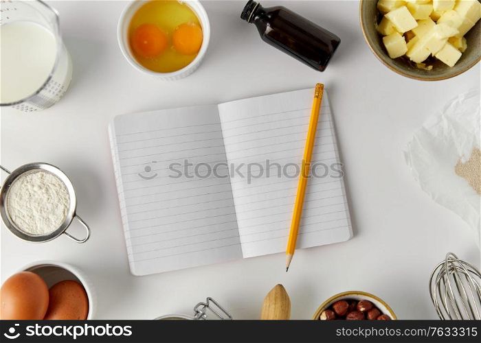 food and culinary concept - empty recipe book with pencil and cooking ingredients on table. recipe book and cooking ingredients on table