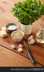 food and culinary concept - parmesan cheese, pine nuts, vinegar and garlic for basil pesto sauce making on wooden table. ingredients for basil pesto sauce on wooden table