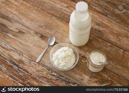 food and dairy products concept - bottle of milk, cottage cheese and homemade yogurt on wooden table. milk, cottage cheese and homemade yogurt