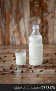 food and dairy products concept - glass and bottle of milk and almond nuts on wooden table. milk and almonds on wooden table