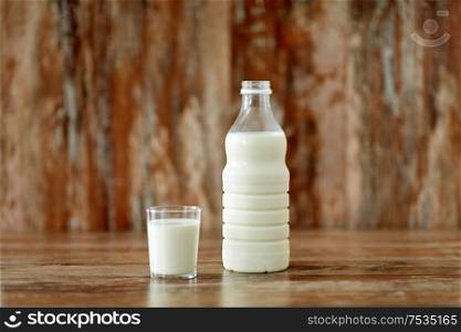 food and dairy products concept - glass and bottle of milk on wooden table. glass and bottle of milk on wooden table