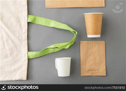 food and drink packaging, recycling and reuse concept - takeaway paper coffee cups and canvas shopping bag on grey background. takeaway food and drink packaging stuff