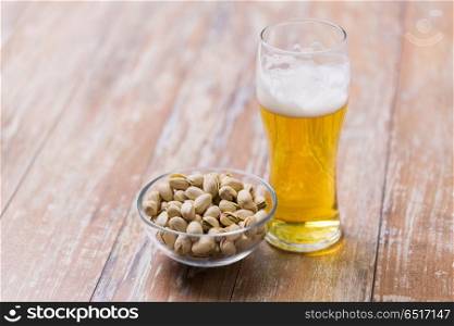 food and drinks concept - glass of draught beer and pistachio nuts on table. glass of draught beer and pistachio nuts on table. glass of draught beer and pistachio nuts on table