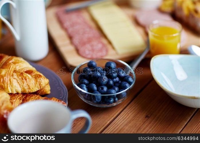food and eating concept - bowl of blueberries on wooden table at breakfast. bowl of blueberries on wooden table at breakfast