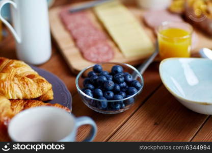 food and eating concept - bowl of blueberries on wooden table at breakfast. bowl of blueberries on wooden table at breakfast