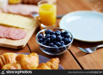 food and eating concept - bowl of blueberries on wooden table at breakfast. bowl of blueberries on wooden table at breakfast