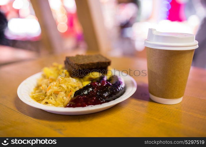 food and eating concept - braised cabbage, potato, rye bread and sausages with cranberry sauce on plate. braised cabbage and sausages with sauce on plate