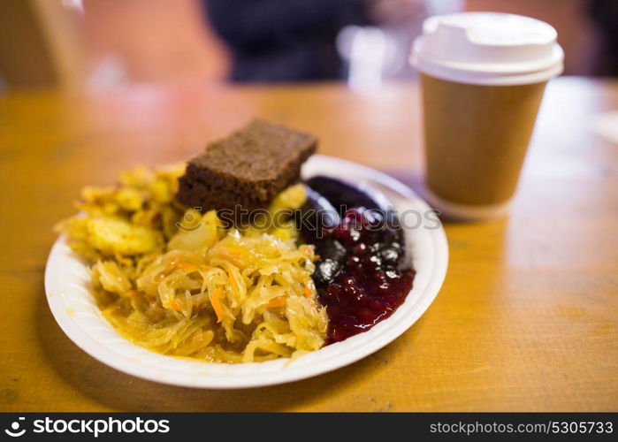 food and eating concept - braised cabbage, potato, rye bread and sausages with cranberry sauce on plate. braised cabbage and sausages with sauce on plate