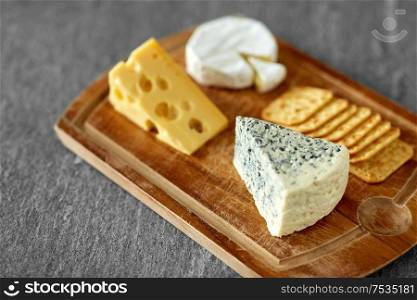 food and eating concept - close up of blue cheese and salty crackers on wooden cutting board. close up of blue cheese on wooden cutting board
