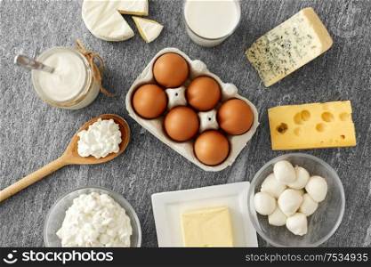 food and eating concept - close up of cottage cheese, bottle of milk, homemade yogurt with butter and chicken eggs on stone table. milk, yogurt, eggs, cottage cheese and butter
