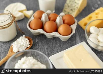 food and eating concept - close up of cottage cheese, bottle of milk, homemade yogurt with butter and chicken eggs on stone table. milk, yogurt, eggs, cottage cheese and butter
