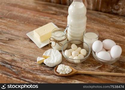 food and eating concept - close up of cottage cheese, bottle of milk, homemade yogurt with butter and chicken eggs on wooden table. milk, yogurt, eggs, cottage cheese and butter