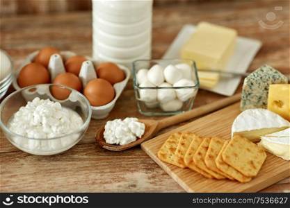 food and eating concept - close up of cottage cheese, crackers, bottle of milk, yogurt with butter and chicken eggs on wooden table. cottage cheese, crackers, milk, yogurt and butter