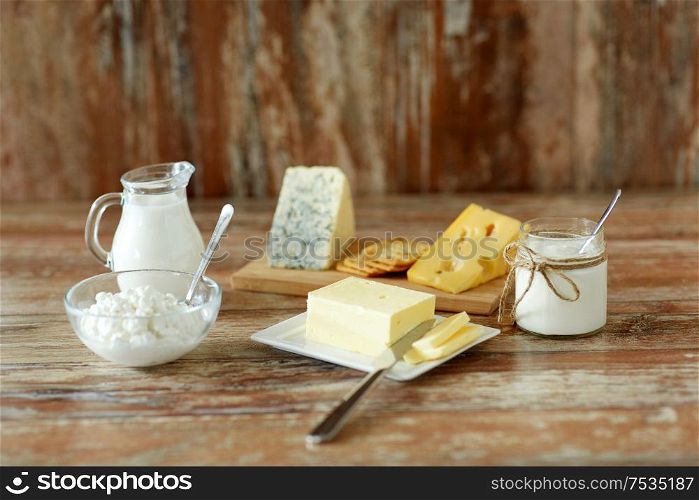 food and eating concept - close up of cottage cheese, crackers, milk, yogurt and butter on wooden table. cottage cheese, crackers, milk, yogurt and butter