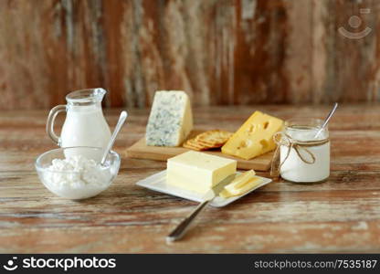 food and eating concept - close up of cottage cheese, crackers, milk, yogurt and butter on wooden table. cottage cheese, crackers, milk, yogurt and butter