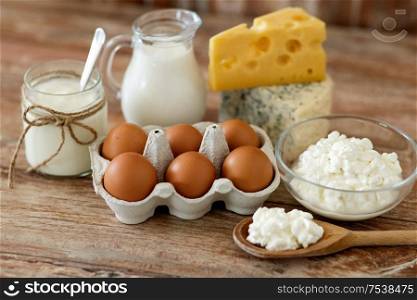 food and eating concept - close up of cottage cheese, jug of milk, homemade yogurt and chicken eggs on wooden table. cottage cheese, milk, yogurt and chicken eggs