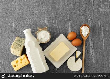 food and eating concept - different kinds of cheese, bottle of milk, yogurt and butter on stone table. different kinds of cheese, milk, yogurt and butter