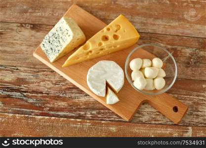 food and eating concept - different kinds of cheese on wooden cutting board. different kinds of cheese on wooden cutting board