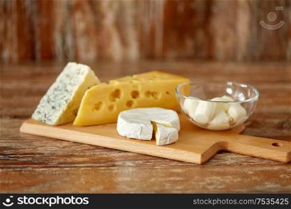 food and eating concept - different kinds of cheese on wooden cutting board. different kinds of cheese on wooden cutting board
