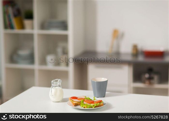 food and eating concept - sandwiches with coffee cup and cream for breakfast on table at home kitchen. sandwiches with coffee and cream at home kitchen