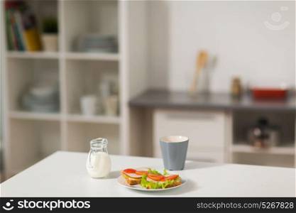 food and eating concept - sandwiches with coffee cup and cream for breakfast on table at home kitchen. sandwiches with coffee and cream at home kitchen