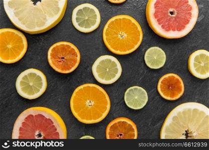 food and healthy eating concept - close up of grapefruit, orange, pomelo, lemon and lime slices on stone background. close up of different citrus fruit slices