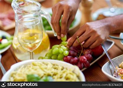 food and healthy eating concept - hands taking grape from plate with fruits. hands taking grape from plate with fruits