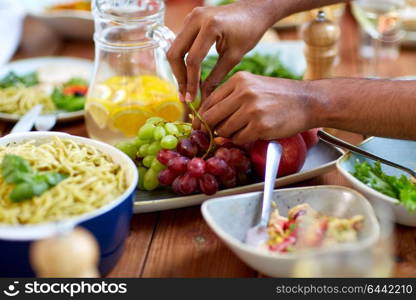 food and healthy eating concept - hands taking grape from plate with fruits. hands taking grape from plate with fruits