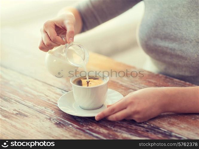 food and home concept - close up of female pouring milk into coffee