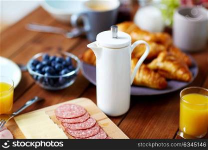 food and hot drinks concept - coffee pot on wooden table at breakfast. coffee pot and food on served table at breakfast