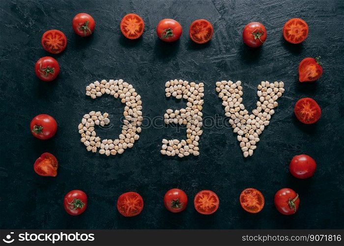 Food and nutrition concept. Horizontal shot of dry garbanzo in form of letter VEG, denoting products for vegans. Tomato frame around